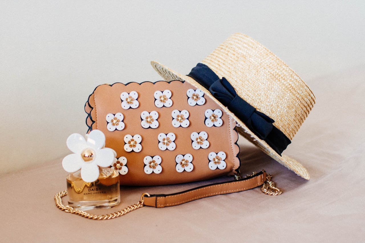 Chic ensemble featuring a floral handbag, straw hat, and perfume, perfect for summer fashion.